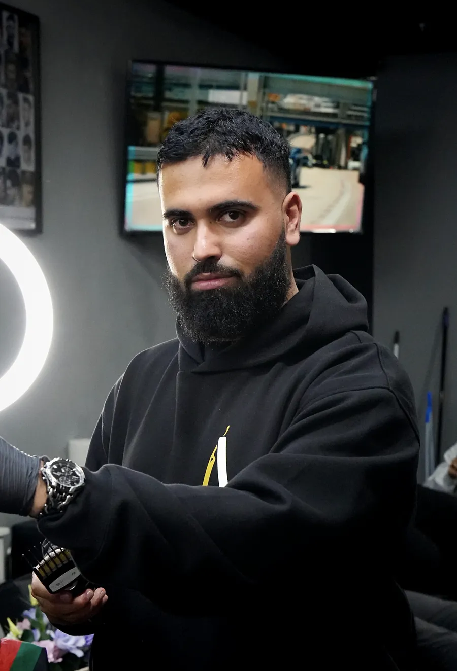 Sami, barber at Atta Barbershop, holding clippers