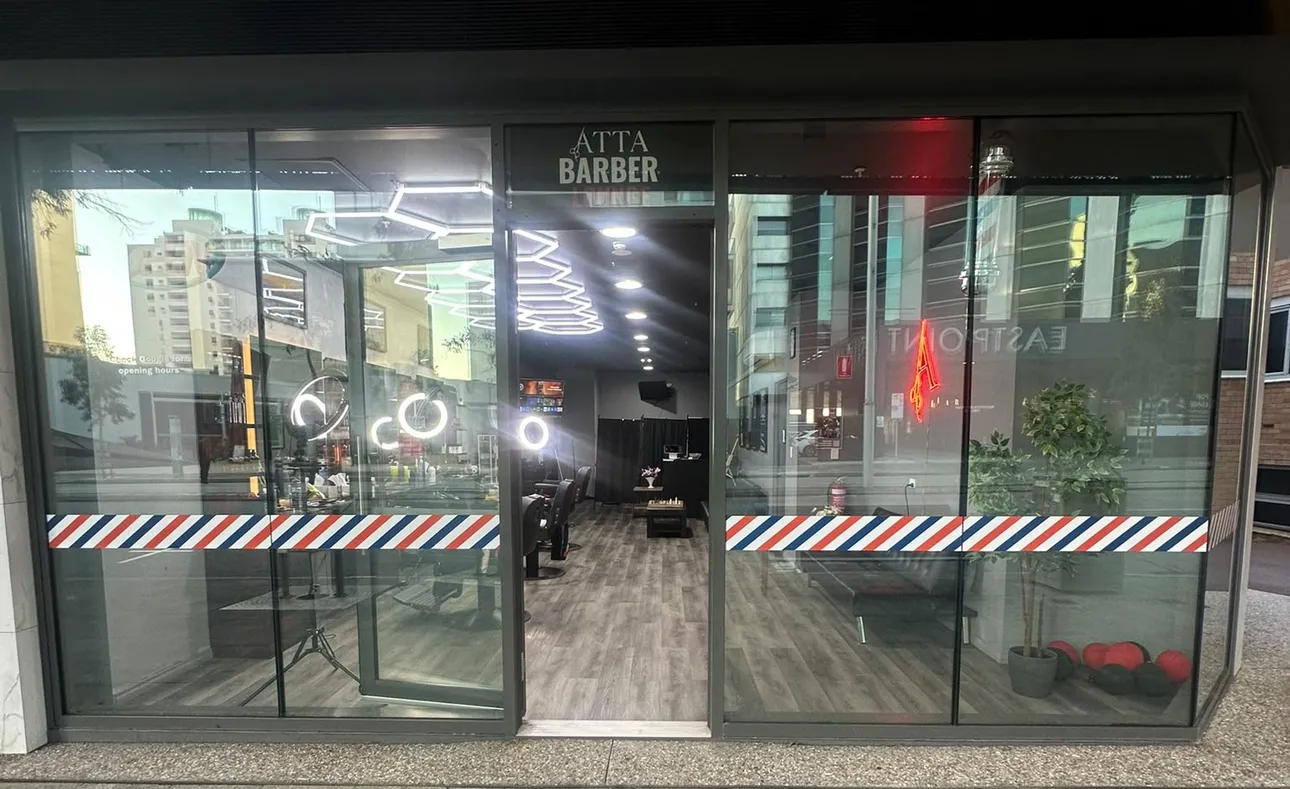 The Atta Barbershop shopfront, glass doors with the barber-pole stripe